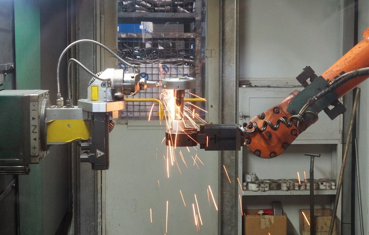 about-us A robotic arm welding in an industrial setting, emitting bright sparks.